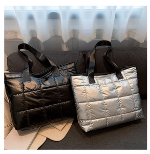 Close-up of quilted nylon tote bags in black and silver finishes on a sofa