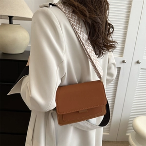 Borsa a tracolla marrone vintage con ampia tracolla geometrica indossata da modella