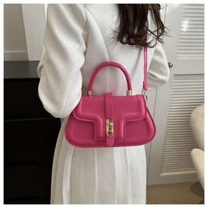 Hot pink saddle bag styled by a model in a modern interior, featuring gold metal buckle
