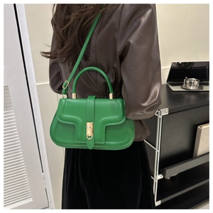 Detailed side view of a green leather saddle bag with gold buckle on a shoulder strap