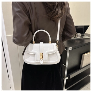 Minimalist white faux leather shoulder bag with gold metal lock worn by a model