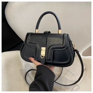 Detail of a vintage black leather saddle bag with a gold buckle and round top handle