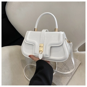 Close-up of a white leather saddle bag featuring a gold buckle and wave-shaped flap