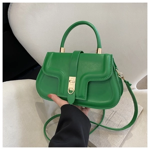 Detail of green saddle bag with golden square lock and adjustable shoulder strap