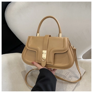 Detail of khaki saddle bag with embossed wave pattern and golden round metal buckle