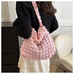 Pink seersucker shoulder bag with elastic textured fabric worn by a model in soft light
