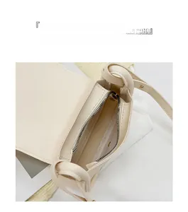 Vue intérieure du sac selle crème montrant le compartiment zippé et les rangements pratiques
