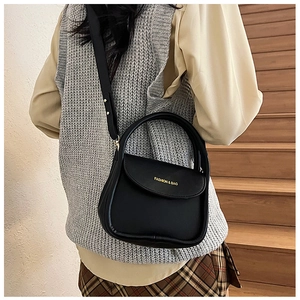 Detail of black leather handbag featuring gold Fashion lettering and elegant flap design