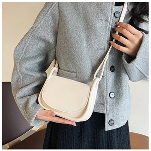 Sacoche selle blanc crème chic portée avec un manteau en laine gris au style moderne