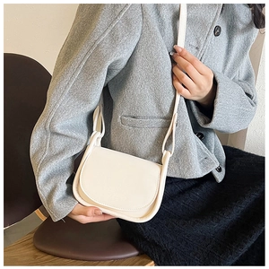 Gros plan d'un sac besace en cuir blanc crème sur un mannequin en veste de tweed