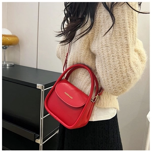 Close-up of a red leather mini crossbody bag with gold FASHION & BAG lettering