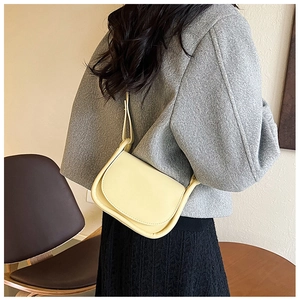 Vue de dos d'un mannequin portant un sac besace minimaliste en cuir synthétique crème