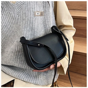 Détail d'un sac besace minimaliste en cuir noir avec bandoulière porté par un mannequin