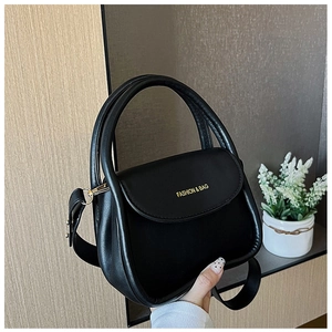 Detail of a black leather handbag with a top handle and gold 'FASHION & BAG' lettering