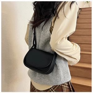 Vue latérale d'un sac besace noir en cuir sur un mannequin avec bandoulière réglable