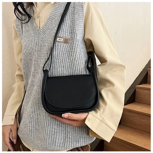Détail du sac selle noir minimaliste avec bandoulière réglable porté par un mannequin