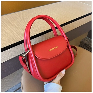 Close-up of red leather handbag showing the FASHION & BAG lettering and sturdy round handle