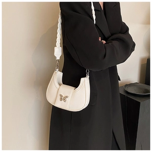 Detail of cream half-moon bag with woven strap and silver butterfly buckle on model