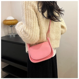 Vue arrière d'un sac besace rose en cuir porté avec un pull en maille crème