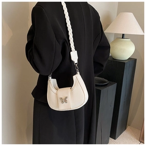 Detail of white hobo crescent bag with metal butterfly clasp and woven shoulder strap