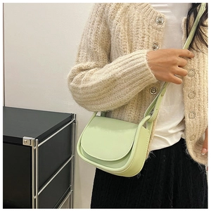 Détail d'un mini sac selle vert menthe avec texture lisse et longue bandoulière