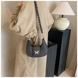 Close-up of black half-moon shoulder bag with golden butterfly buckle and woven strap