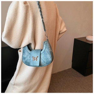 Close-up of blue crescent bag with silver butterfly buckle and woven shoulder strap