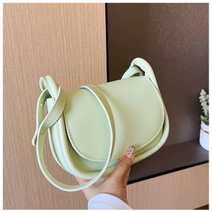 Gros plan sur un sac selle vert menthe avec texture cuir mat et détails de couture