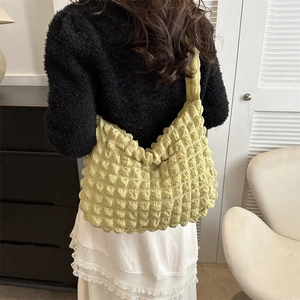 Light green hobo bag with bubble texture shown on model in a stylish casual pose