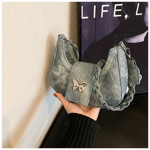 Detail of light blue denim crescent bag with silver butterfly buckle and woven handle