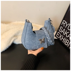 Detailed view of denim crescent bag with silver butterfly charm and braided handle