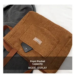 Dettaglio della tasca anteriore di una borsa tote in pile marrone con smartphone