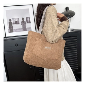 Detail of brown teddy fleece tote bag with fashion label and light gray straps
