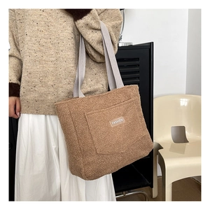 Sac cabas en polaire marron avec bandoulières grises et écusson mode porté à l'épaule