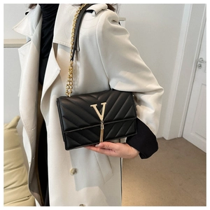Détail du sac bandoulière noir matelassé avec logo V doré et pampille métallique