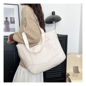 Close-up of off-white faux shearling tote bag with FASHION patch and wide shoulder strap
