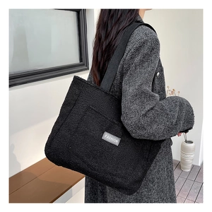 Détail du sac cabas noir en polaire montrant la texture douce et l'étiquette tissée