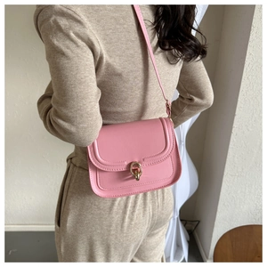 Détail d'un sac bandoulière rose avec boucle mors dorée et surpiqûres décoratives