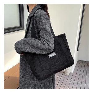 Detailed texture of black plush faux fur tote bag with a white fashion label