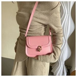 Détail du sac à bandoulière rose avec boucle dorée sur une tenue beige élégante