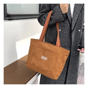 Dettaglio della borsa tote in pile orsetto caramello con etichetta indossata da una modella