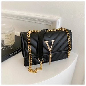 Détail d'un sac bandoulière matelassé noir avec logo V doré et pampille élégante
