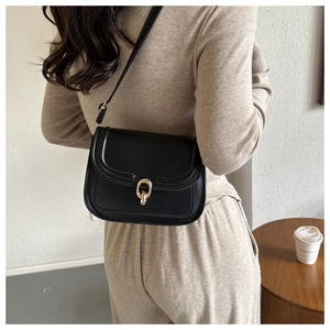 Détail d'un sac bandoulière noir avec fermoir en fer à cheval doré et bandoulière réglable