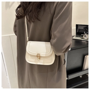 Détail d'un sac bandoulière crème en similicuir avec boucle ronde en métal doré poli