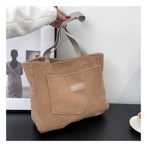 Dettaglio ravvicinato della borsa tote in pile sherpa kaki con etichetta e manici grigi