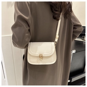 Sac bandoulière beige avec boucle fer à cheval dorée et coutures sur un mannequin