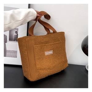 Dettaglio borsa tote marrone in peluche con etichetta FASHION e tracolla intrecciata
