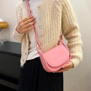 Sacoche selle minimaliste en cuir PU rose portée avec un cardigan beige chic