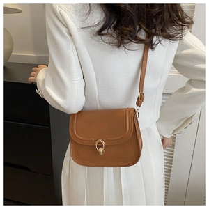 Sac bandoulière vintage marron avec boucle dorée porté par un mannequin élégant