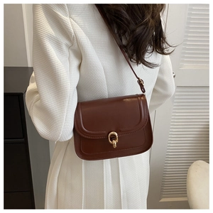 Détail d'un sac à bandoulière en cuir marron avec boucle dorée ovale et rabat élégant